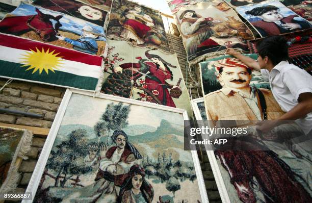 An Iraqi Kurd hangs a carpet with the image of Kurdish regional president Massud Barzani who is also the leader of Kurdistan Democratic Party in the...