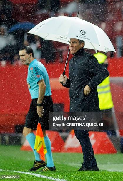 Sevilla's Argentinian coach Eduardo Berizzo holds an umbrella as he stands on the sideline during the Spanish league football match Sevilla FC vs...