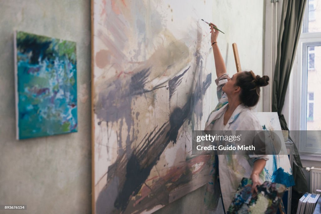 Woman painting a big work in studio.