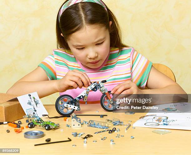 8 year old girl constructing model of motorcycle. - scatola di montaggio foto e immagini stock