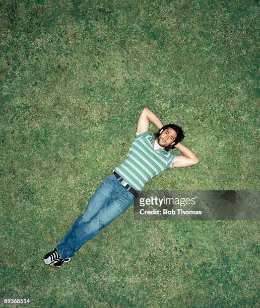 young man laying on grass - lying down stockfoto's en -beelden