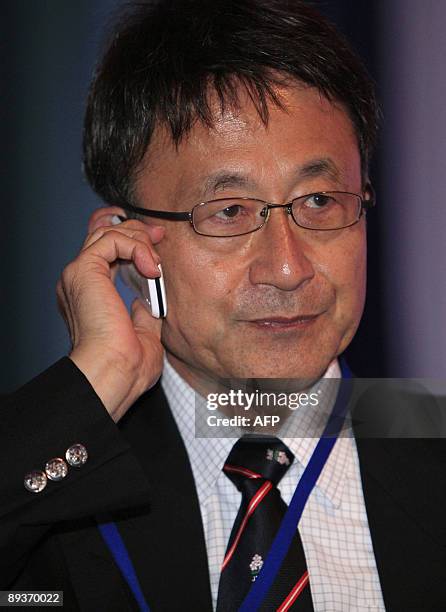 Japan's rugby union team media manager Koji Tkumasu speaks on the phone ahead of the 24-man council of the International Rugby Board's decision of...