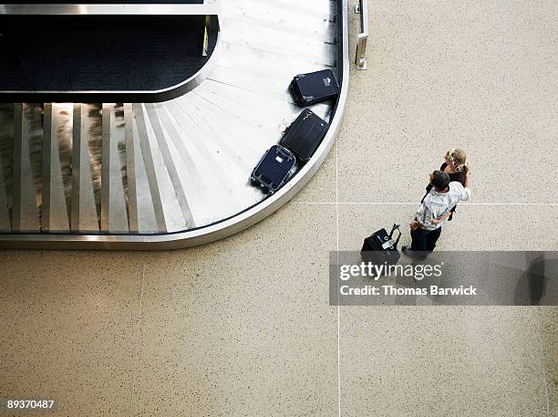 couple waiting for luggage at baggage claim  - luggage stock pictures, royalty-free photos & images