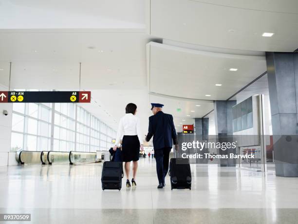 pilot and flight attendant walking through airport - carrying sign stock-fotos und bilder