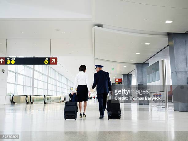 pilot and flight attendant walking through airport - carrying sign ストックフォトと画像