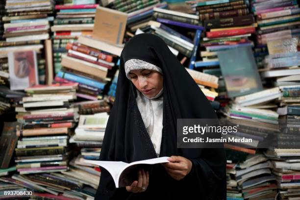 Muslim woman reading book in open book store
