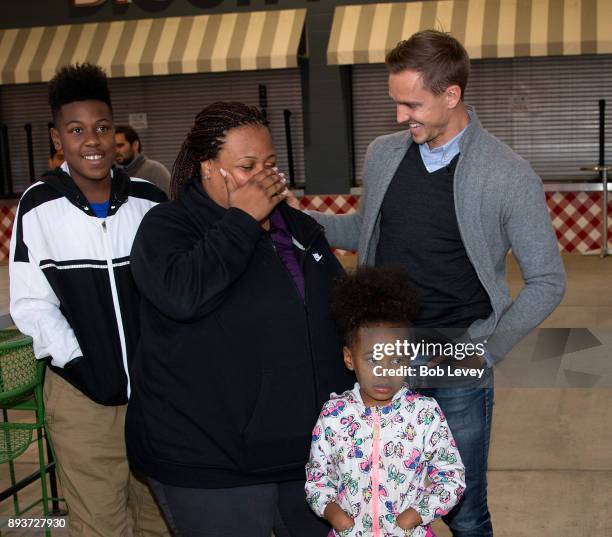 Stu Holden hands out gifts to Patrizia McQueen and family during the Kick in for Houston participants and Leesa Sleep surprise familes affected by...