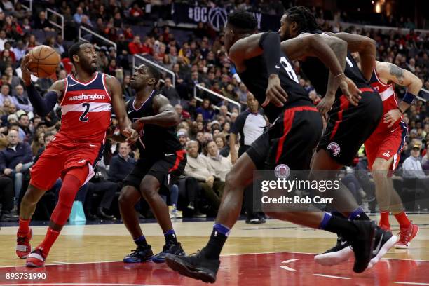 John Wall of the Washington Wizards passes the ball around Jawun Evans of the LA Clippers in the second half at Capital One Arena on December 15,...