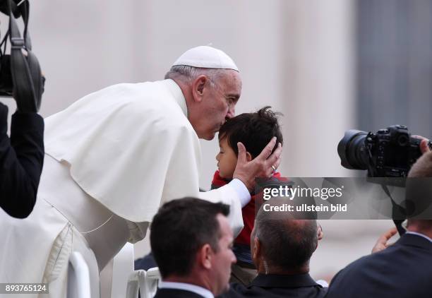 Rom, Vatikan Papst Franziskus I. Umgeben von Bodyguards kueest und segnet er einen kleinen Jungen bei der woechentlichen Generalaudienz auf dem...