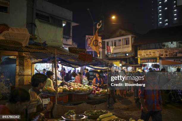 Pedestrians walk past a vegetable stall in Mumbai, India, on Friday, Dec. 15, 2017. India's inflation surged past the central bank's target,...