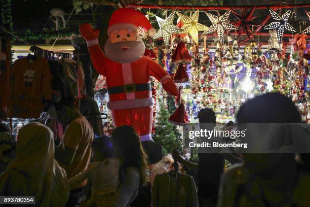 Pedestrians and shoppers walk past a stall selling festive Christmas decorations in Mumbai, India, on Friday, Dec. 15, 2017. India's inflation surged...