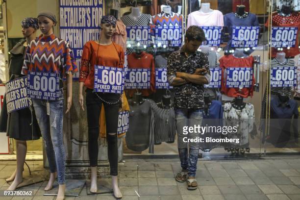 Man stands next to mannequins outside a clothing store in Mumbai, India, on Friday, Dec. 15, 2017. India's inflation surged past the central bank's...