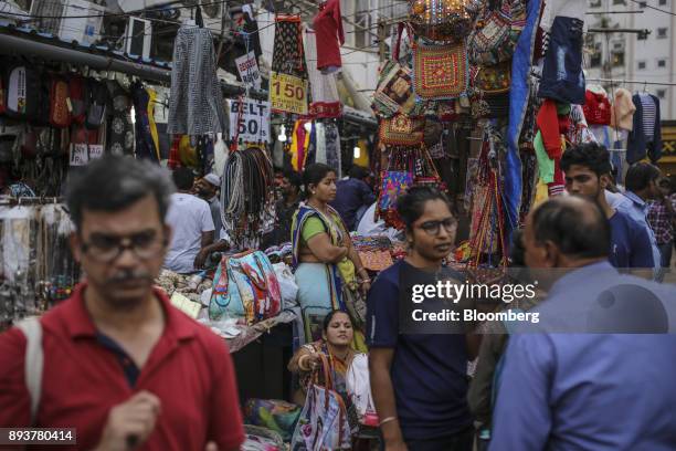 Pedestrians and shoppers walk past handbags on display at a roadside stall in Mumbai, India, on Friday, Dec. 15, 2017. India's inflation surged past...