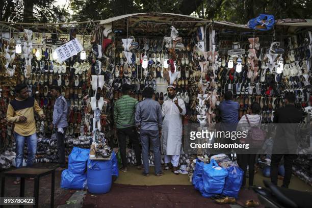 Shoppers look at shoes displayed for sale at a roadside stall in Mumbai, India, on Friday, Dec. 15, 2017. India's inflation surged past the central...