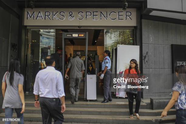 Customer walks through a metal detector as he enters a Marks & Spencer Group Plc store in Mumbai, India, on Friday, Dec. 15, 2017. India's inflation...