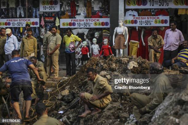 Workers labor on a road under construction in front of a clothing store in Mumbai, India, on Friday, Dec. 15, 2017. India's inflation surged past the...