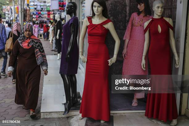 Pedestrians walk past mannequins displayed outside a clothing store in Mumbai, India, on Friday, Dec. 15, 2017. India's inflation surged past the...