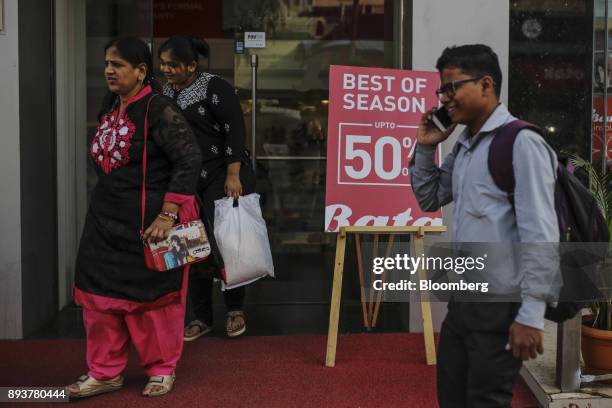 Shoppers walk past a sale sign displayed outside a store in Mumbai, India, on Friday, Dec. 15, 2017. India's inflation surged past the central bank's...