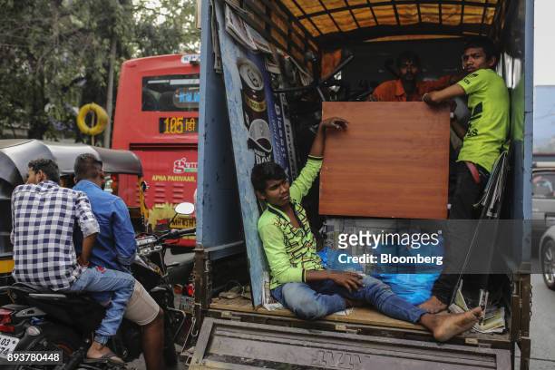 Workers stand and sit inside a truck as they transport goods in Mumbai, India, on Friday, Dec. 15, 2017. India's inflation surged past the central...