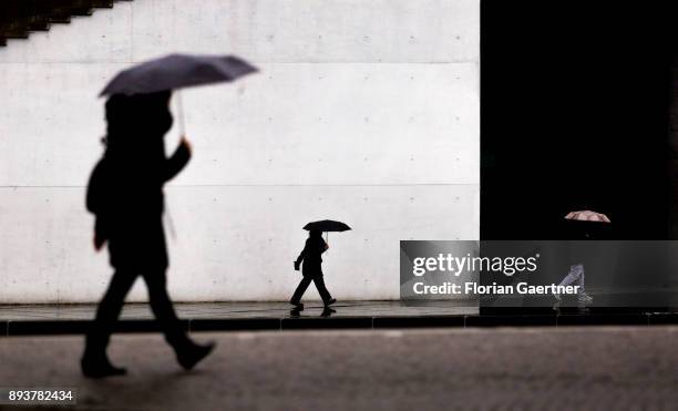 Three persons with umbrella walk along the river Spree on December 15, 2017 in Berlin, Germany.