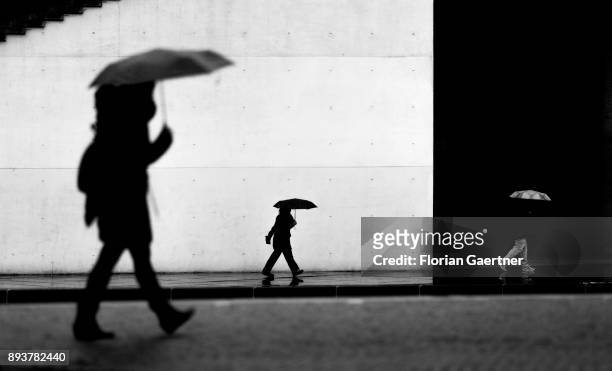Image has been converted to black and white.) BERLIN, GERMANY Three persons with umbrella walk along the river Spree on December 15, 2017 in Berlin,...