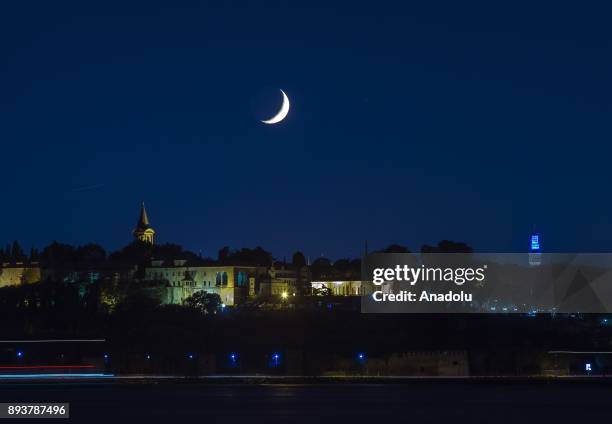 Topkapi Palace and Beyazit Tower at night with crescent moon in the sky in Istanbul, Turkey on August 25, 2017.