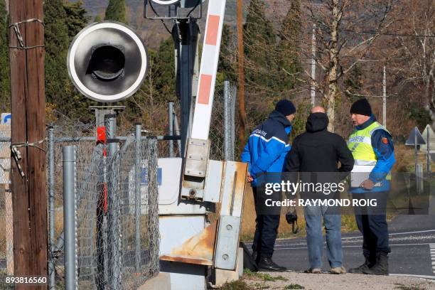 Gendarmes and employees of the National society of French railways investigate at a level crossing in Millas, on December 16 two days after some...