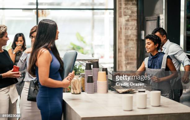 young woman ordering coffee in bar during the coffee break at work - customers lining up stock pictures, royalty-free photos & images