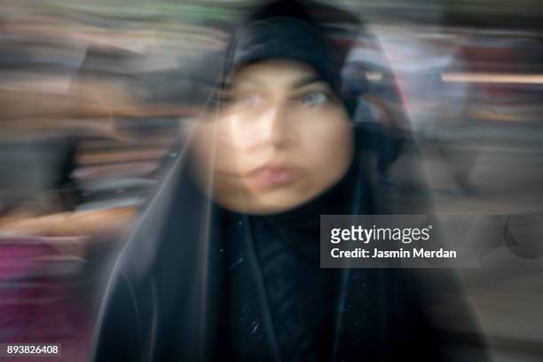 muslim woman standing between crowded people blurred motion walking - iranian culture stock pictures, royalty-free photos & images