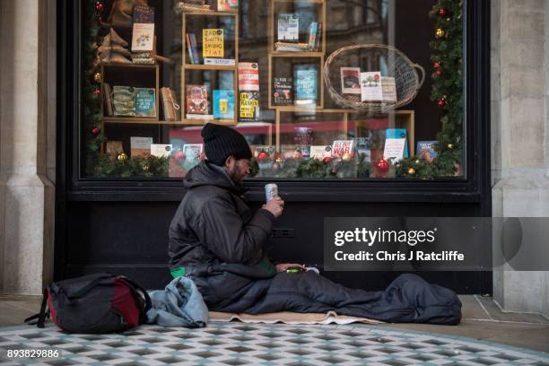 Homeless man drinks a can of beer next to a book shop's Christmas window display on December 16, 2017 in London, England. Homeless charity Shelter...