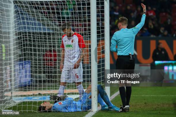 Referee Christian Dingert gestures and Jeffrey Gouweleeuw of Augsburg helps Goalkeeper Marvin Hitz of Augsburg during the Bundesliga match between FC...