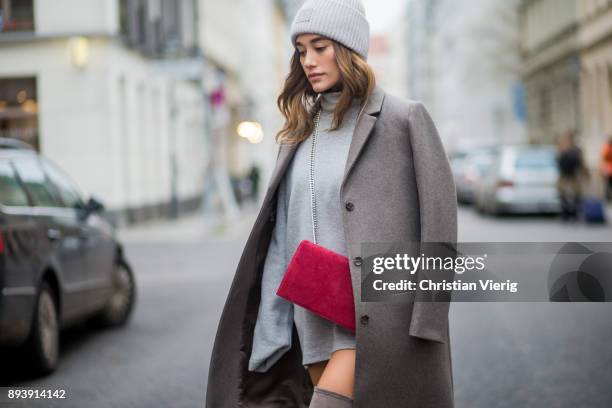 Anna Sharypova wearing Stuart Weitzman overknee boots, a grey COS coat, red Agneel bag, grey COS turtleneck, Acne wool beanie on December 16, 2017 in...