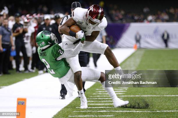 Damion Willis of the Troy Trojans is tackled by Eric Jenkins of the North Texas Mean Green during the first half of the R+L Carriers New Orleans Bowl...