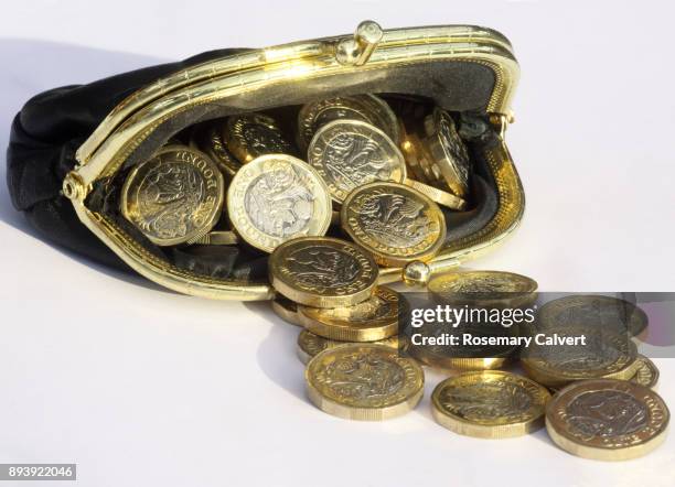 newly minted one pound coins spilling from leather purse. - bolso dorado fotografías e imágenes de stock