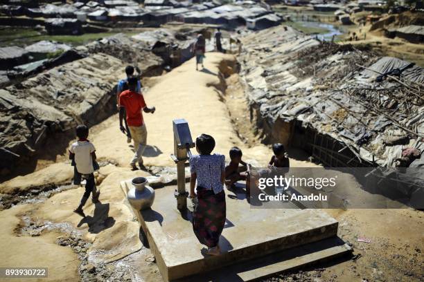 Rohingya kids, who fled from oppression within ongoing military operations in Myanmars Rakhine state, have a bath as a girl pumps water from a...