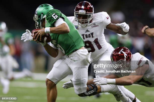 Mason Fine of the North Texas Mean Green is sacked by Kelvin Lucky of the Troy Trojans and Hunter Reese during the second half of the R+L Carriers...
