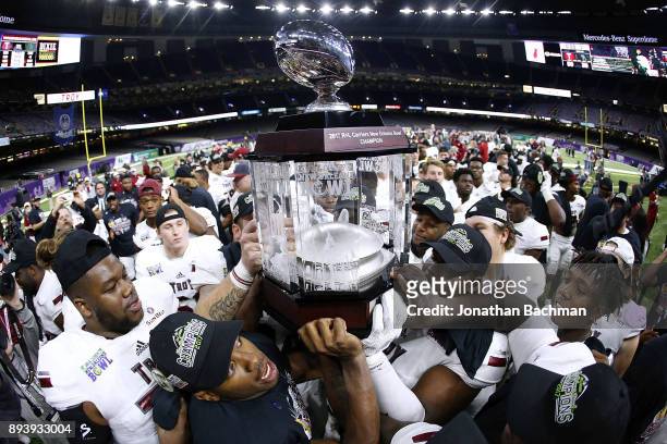The Troy Trojans celebrate with the trophy after winning the R+L Carriers New Orleans Bowl against the North Texas Mean Green at the Mercedes-Benz...