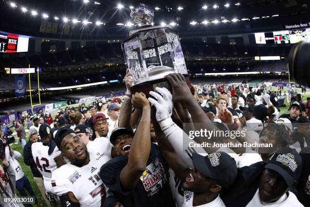 The Troy Trojans celebrate with the trophy after winning the R+L Carriers New Orleans Bowl against the North Texas Mean Green at the Mercedes-Benz...