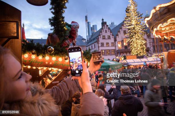 Young woman takes a picture of Christmas market cup at the annual Christmas market at Roemerberg on December 16, 2017 in Frankfurt, Germany....