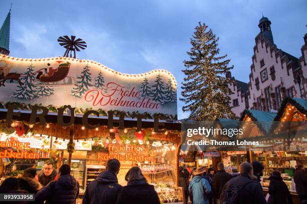 Visitors stand in front of a carousel, walk among stalls selling mulled wine, pastries, sausages, Christmas decorations, handicrafts and other...