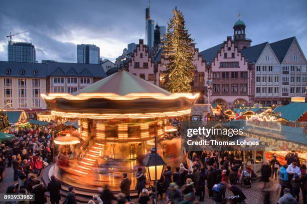 Visitors stand in front of a carousel, walk among stalls selling mulled wine, pastries, sausages, Christmas decorations, handicrafts and other...