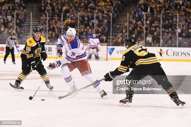 Brady Skjei of the New York Rangers skates with the puck against Noel Acciari and Sean Kurlay of the Boston Bruins at the TD Garden on December 16,...