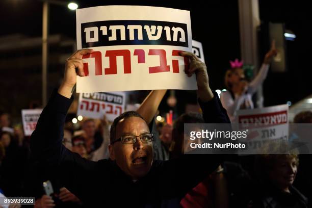 An Israeli man holds a placard, reading 'corrupted go home', as thousands of Israelis protest against goverment corruption in Tel-Aviv, calling for...