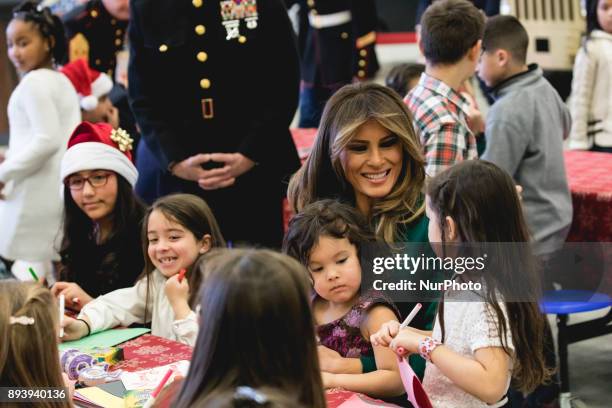 First Lady Melania Trump sits with 3-year-old Mehreem Donahue in her lap, as she makes Christmas cards with military kids, at the Marine Corps'...