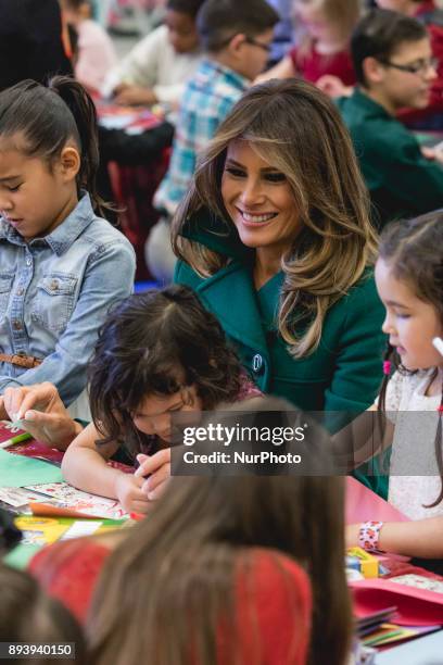 First Lady Melania Trump sits with 3-year-old Mehreem Donahue in her lap, as she makes Christmas cards with military kids, at the Marine Corps'...