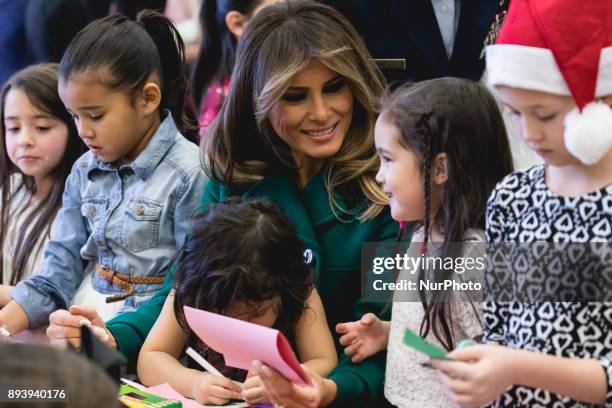 First Lady Melania Trump sits with 3-year-old Mehreem Donahue in her lap, as she makes Christmas cards with military kids, at the Marine Corps'...