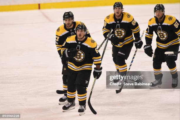 Brad Marchand, Patrice Bergeron, David Pastrnak and Ryan Spooner of the Boston Bruins skate back to the bench to celebrate a third period goal...