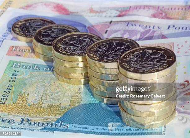 stacks of one pound coins on british pound notes. - british pound sterling stock-fotos und bilder