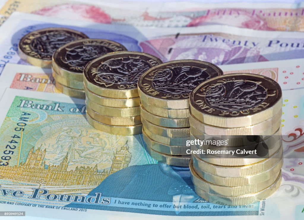 Stacks of one pound coins on British pound notes.