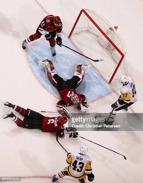 Goaltender Antti Raanta of the Arizona Coyotes makes a save on the puck as Sidney Crosby of the Pittsburgh Penguins attempts to shoot on the rebound...